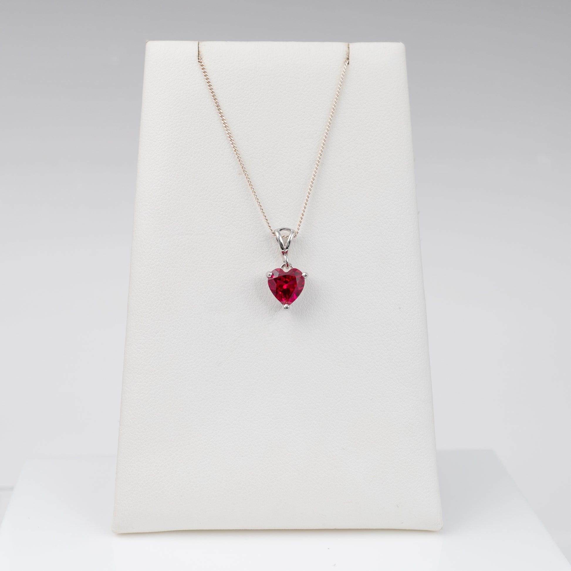 lab-grown ruby heart necklace with split bail on a display stand