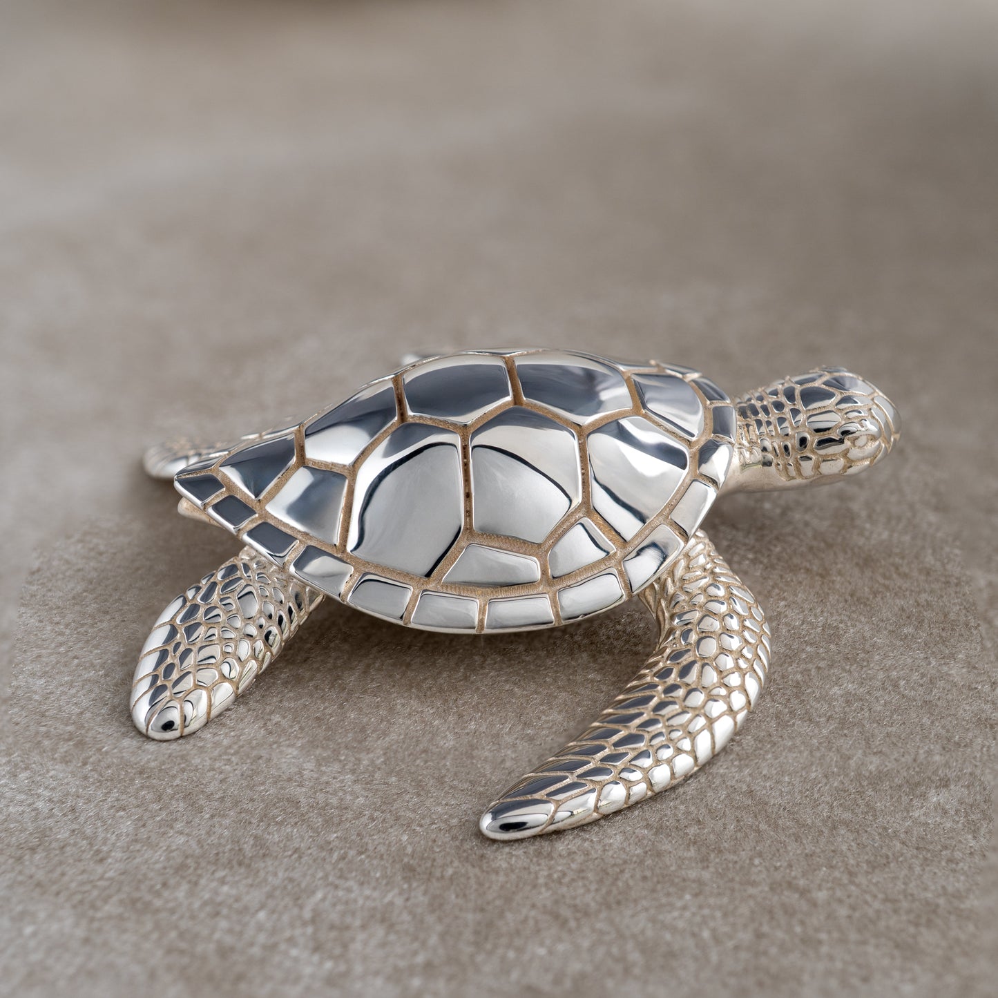 Sterling silver sea turtle figurine angled view on beige background