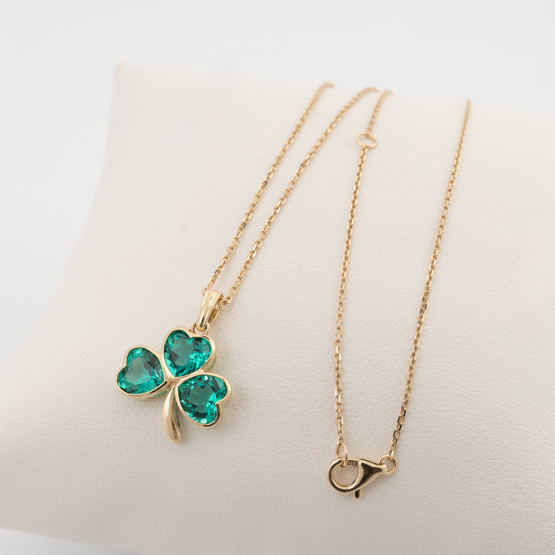 shamrock pendant and adjustable gold chain laid out flat