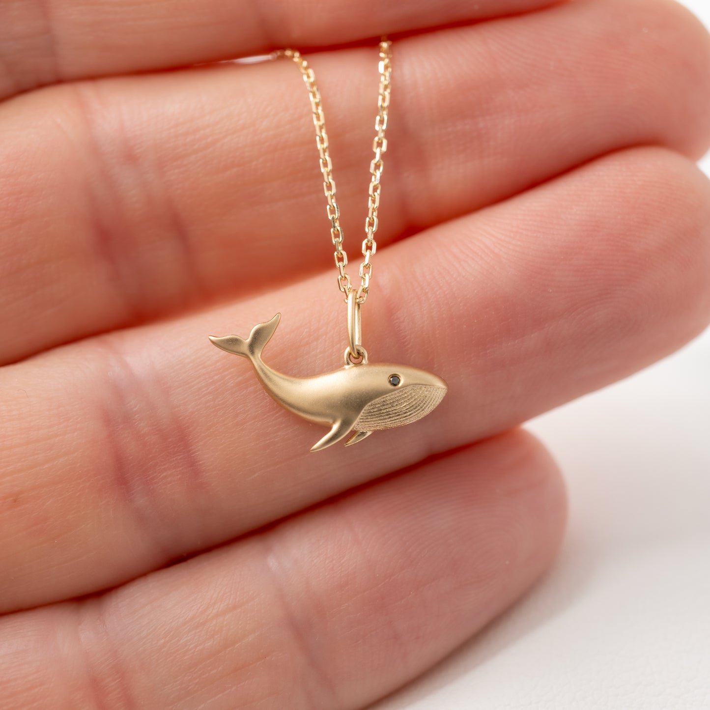 Whale necklace in 9ct gold held in hand to show size