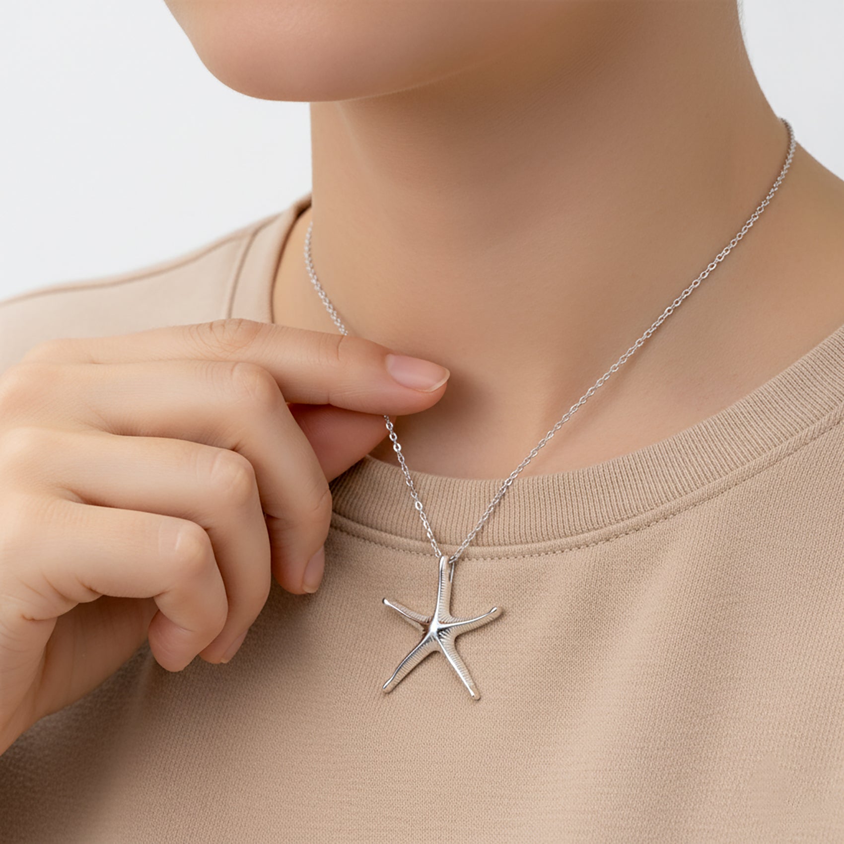Starfish pendant necklace on a person wearing a beige shirt