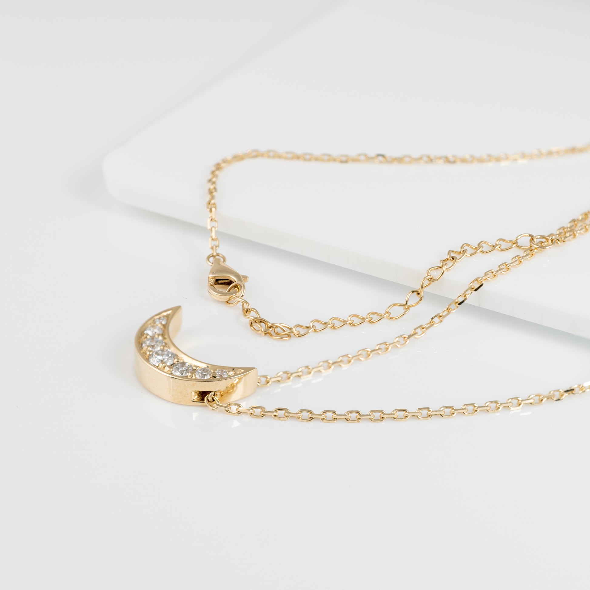 Flat lay of lab diamond crescent moon necklace with adjustable chain