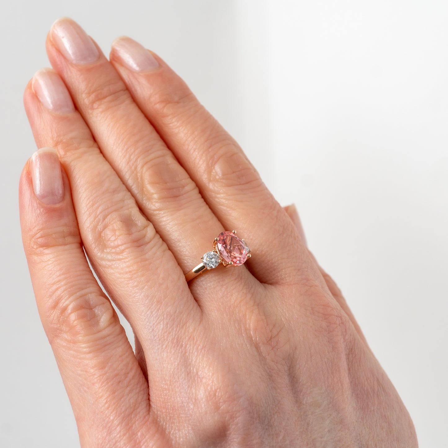 Side view of lab created padparadscha sapphire ring worn on hand by Hunters Fine Jewellery