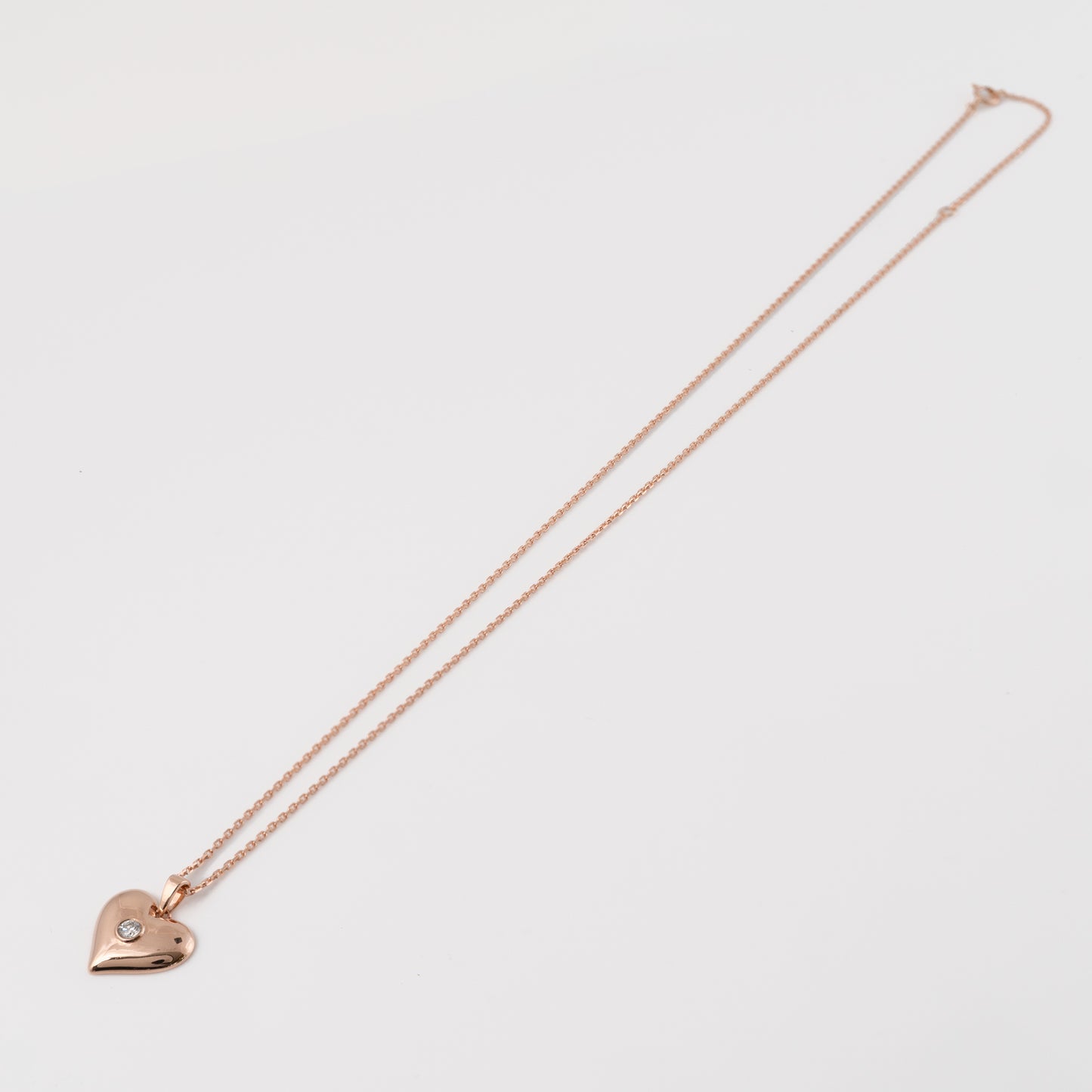 Rose gold necklace with adjustable chain laid on white background to show size