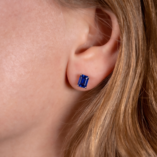 Royal blue sapphire rectangle stud earrings worn on the ear