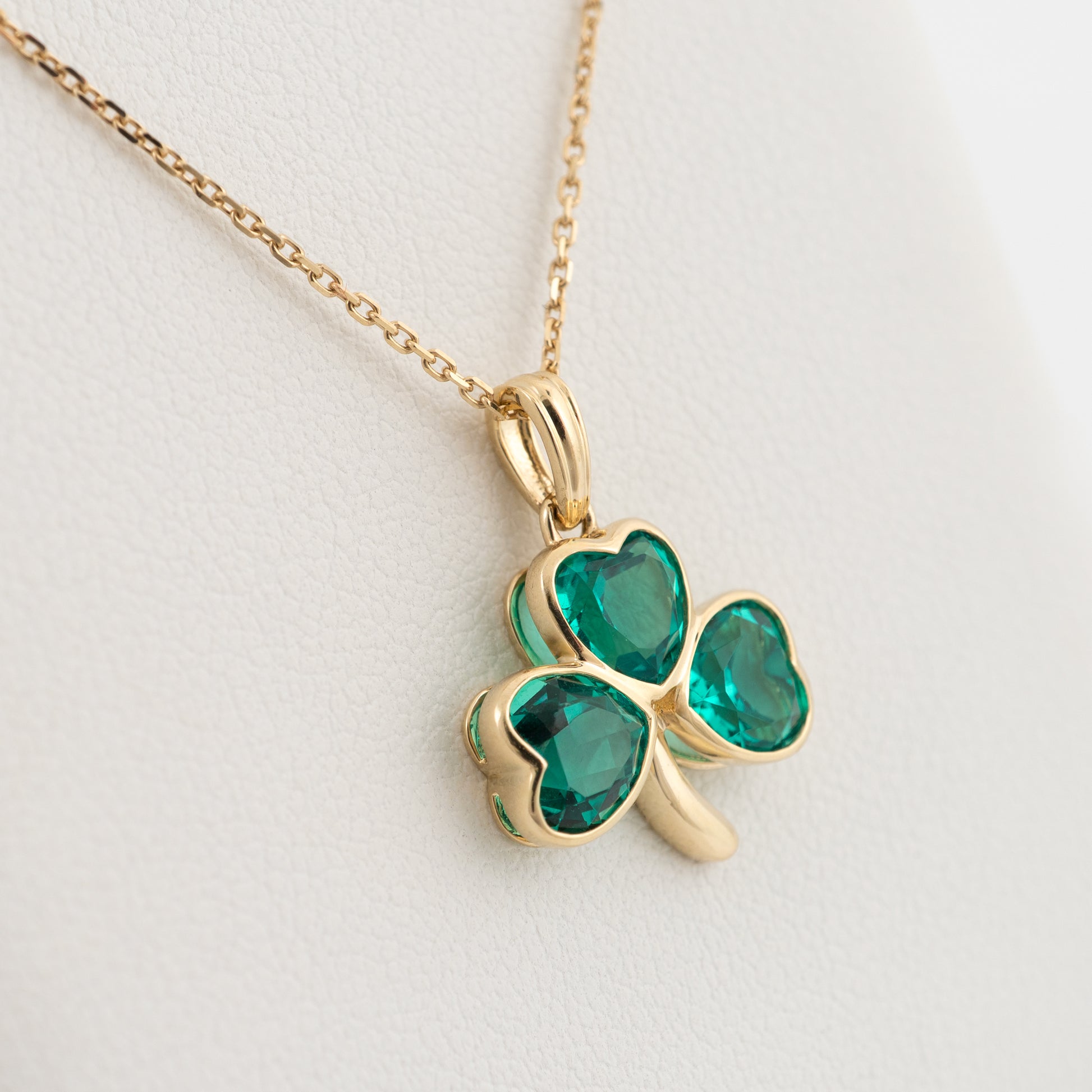 shamrock pendant in yellow gold with lab emeralds on soft cushion