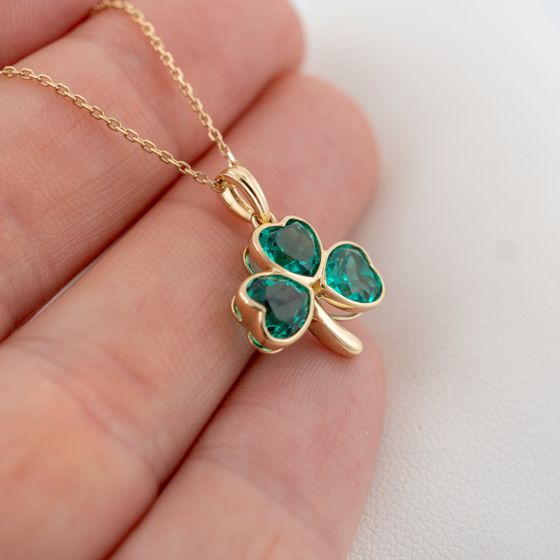 lucky irish shamrock pendant charm with green stones shown in hand for scale