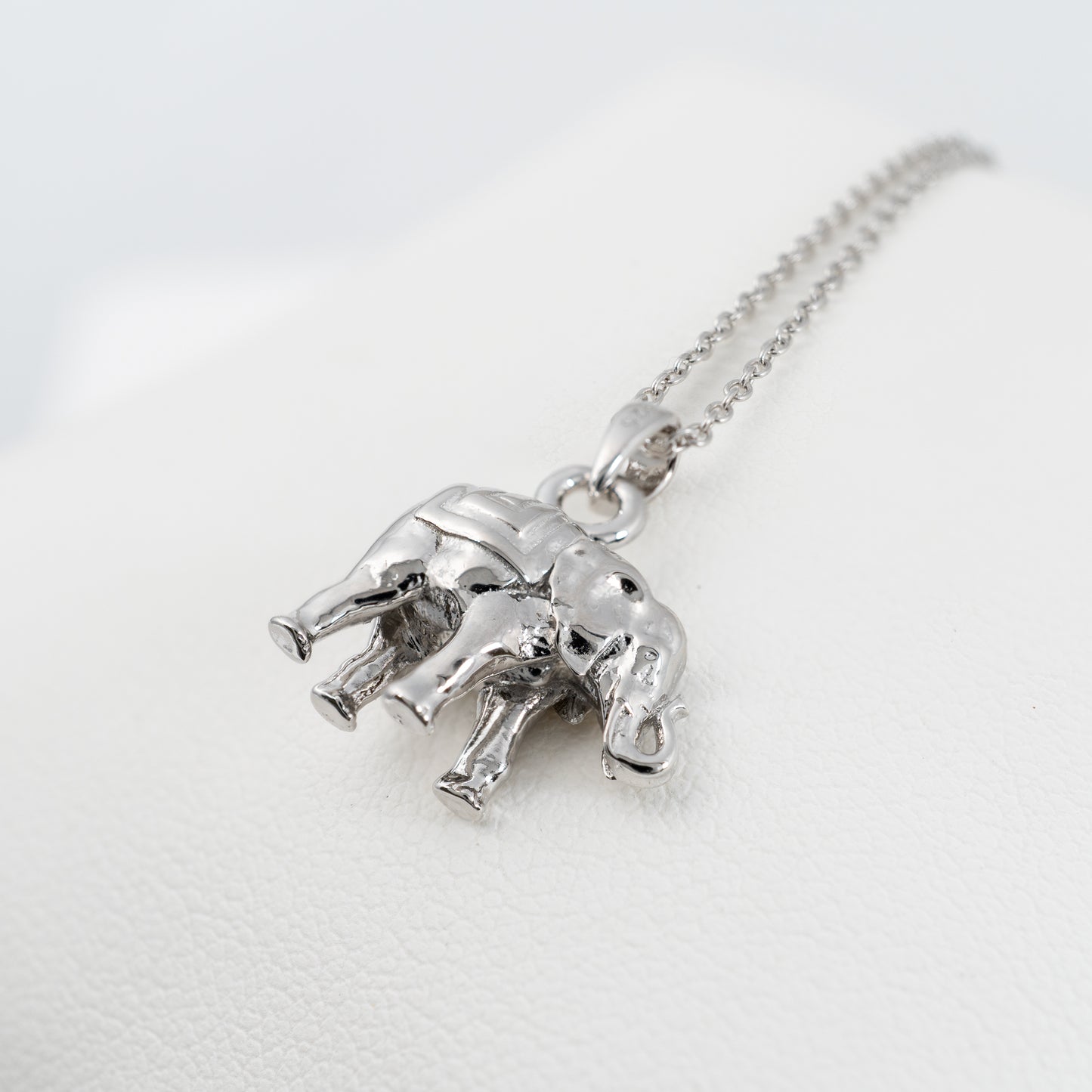 Three-dimensional silver lucky elephant pendant on white leather display