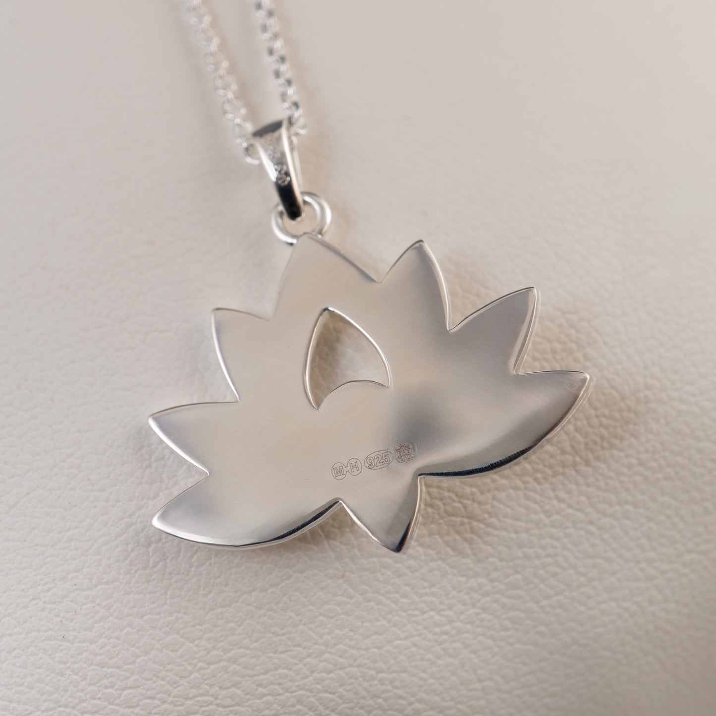 Back view of sterling silver lotus flower pendant showing smooth hallmark surface