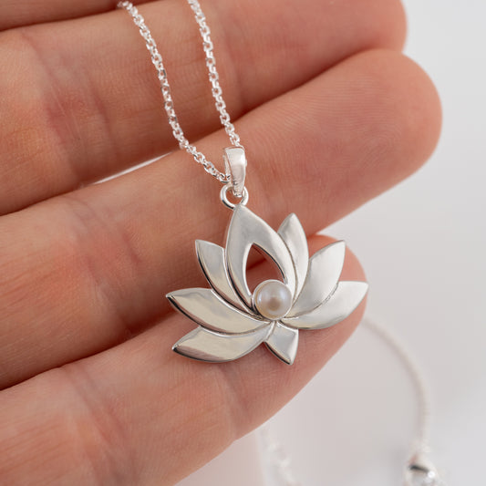 Silver lotus flower necklace with a pearl on a hand against a white background