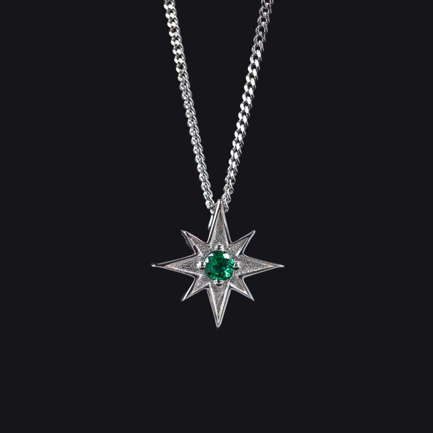 north star pendant with green gemstone on dark grey background representing night sky