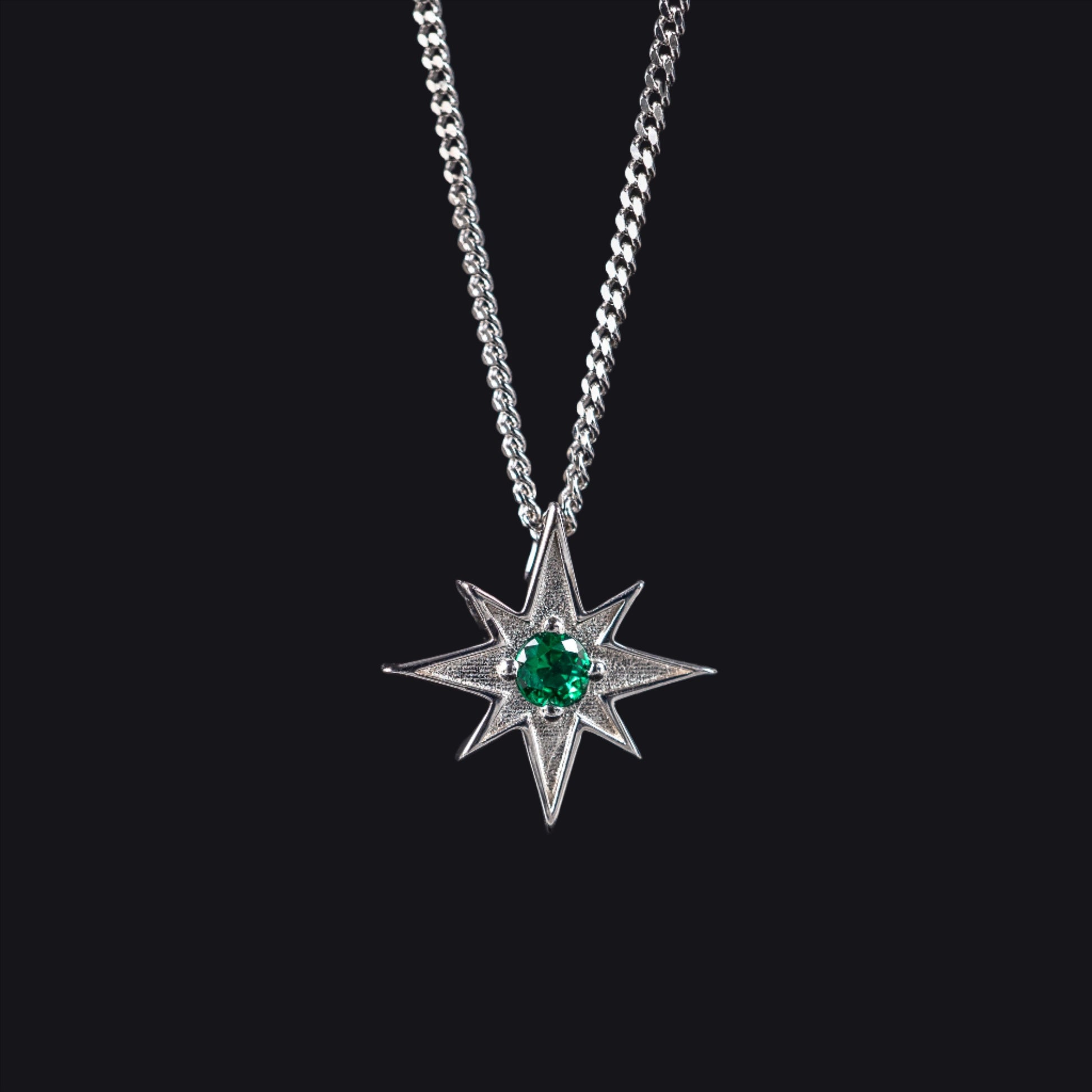 north star pendant with green gemstone on dark grey background representing night sky