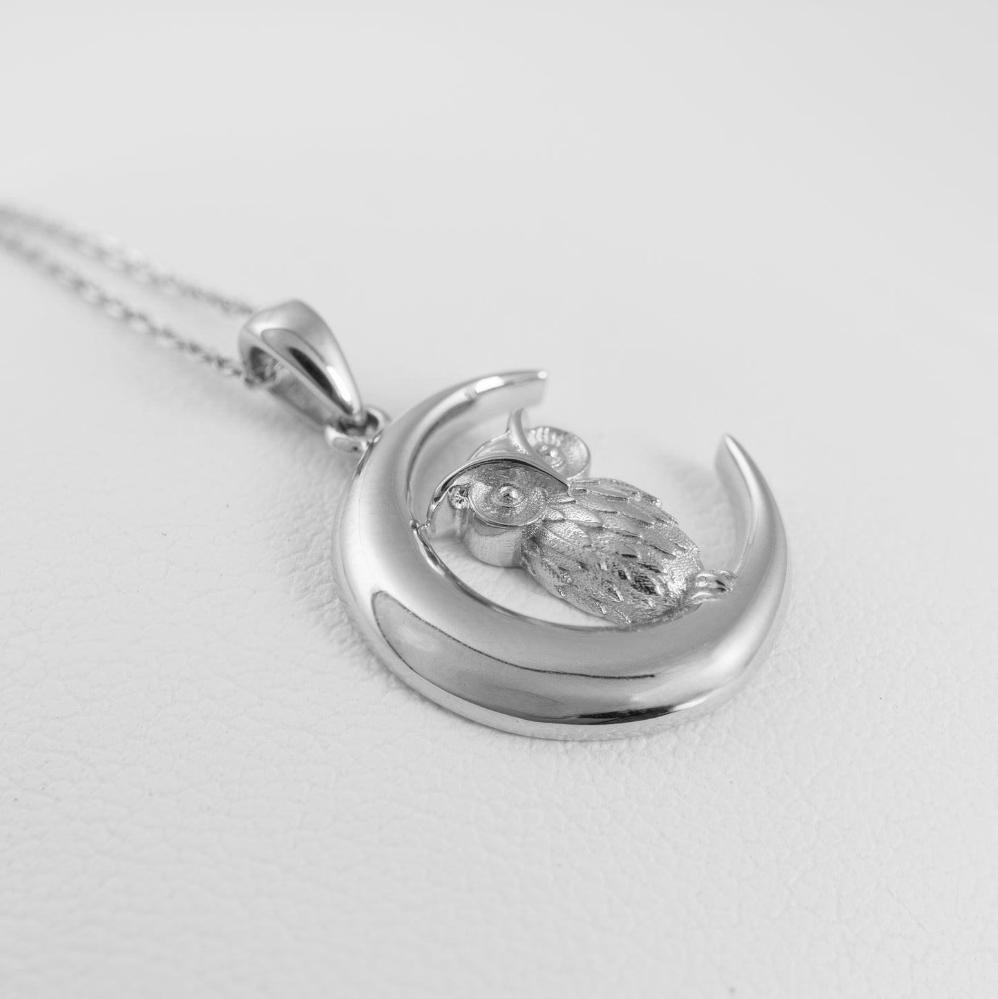 Silver pendant with owl design on a white background