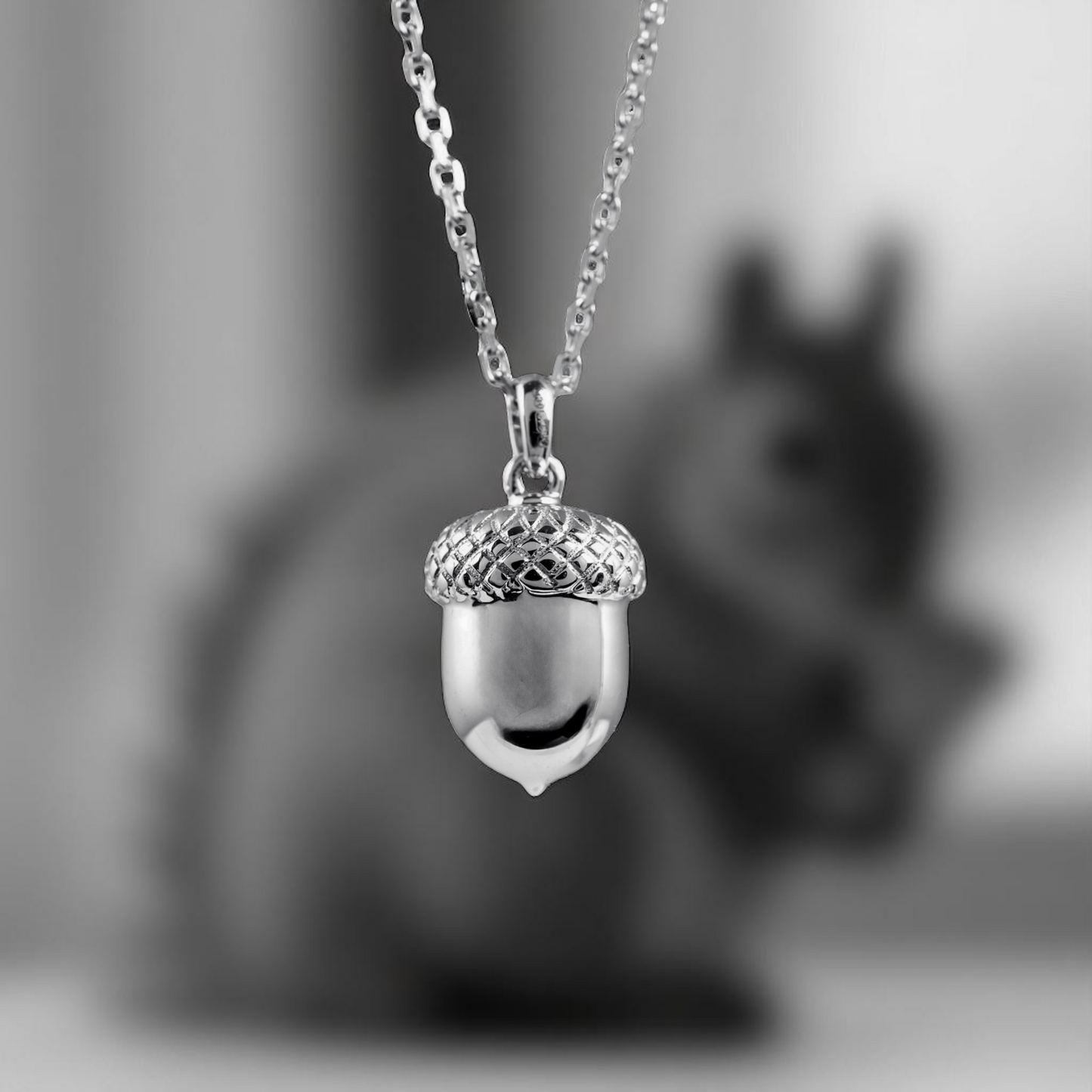 silver acorn necklace hanging infront of a  squirrel