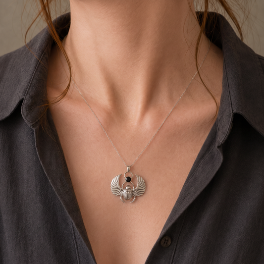Silver scarab pendant with polished black onyx worn by a female model in a dark open shirt, showing the pendant’s scale.