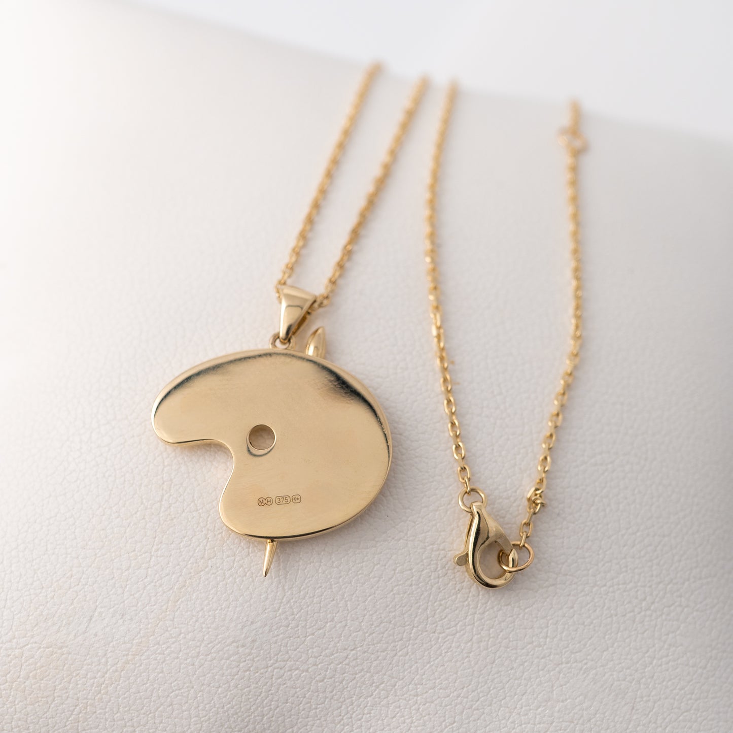Reverse side of the gold artist palette pendant with hallmarks