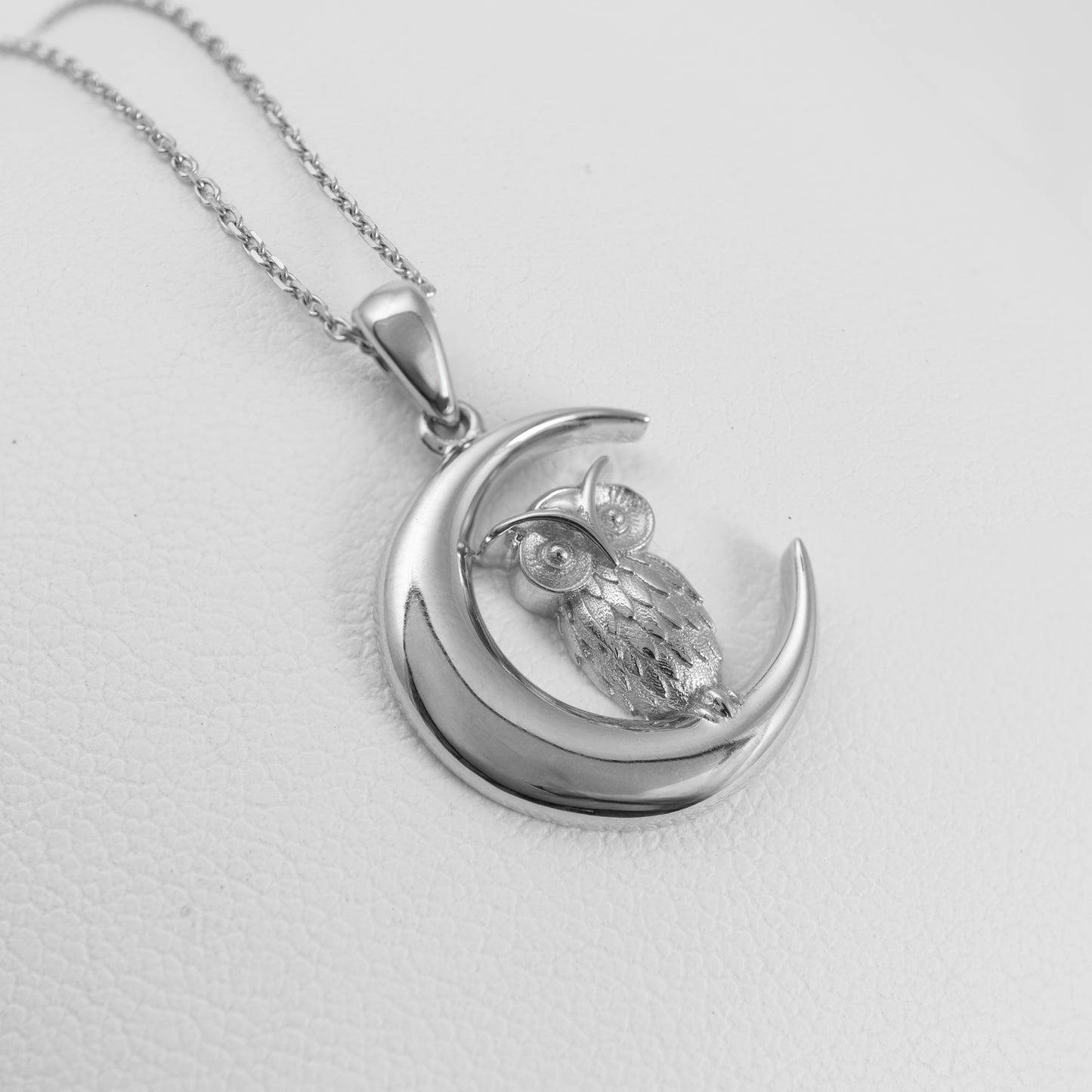 Silver owl pendant on a moon-shaped crescent with a chain on a white background