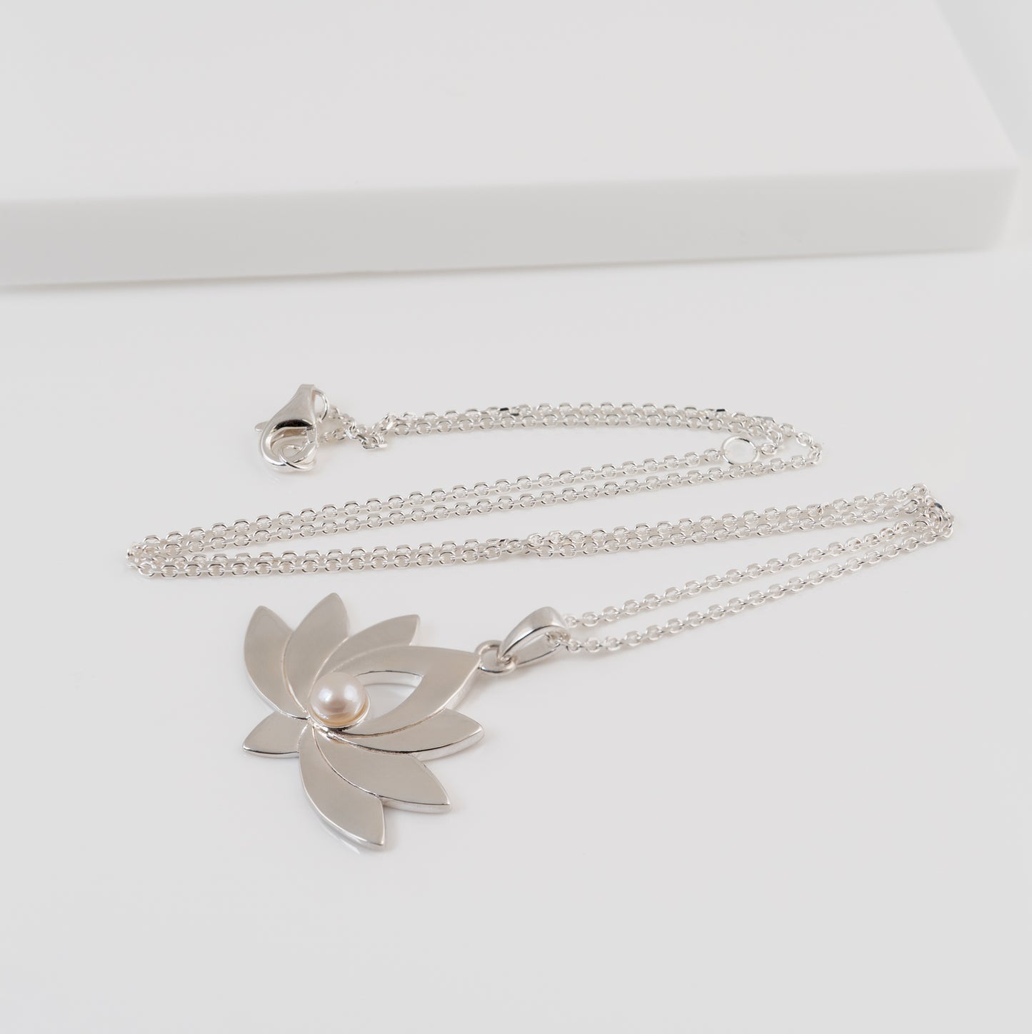 Silver necklace with a lotus flower necklace on a white background