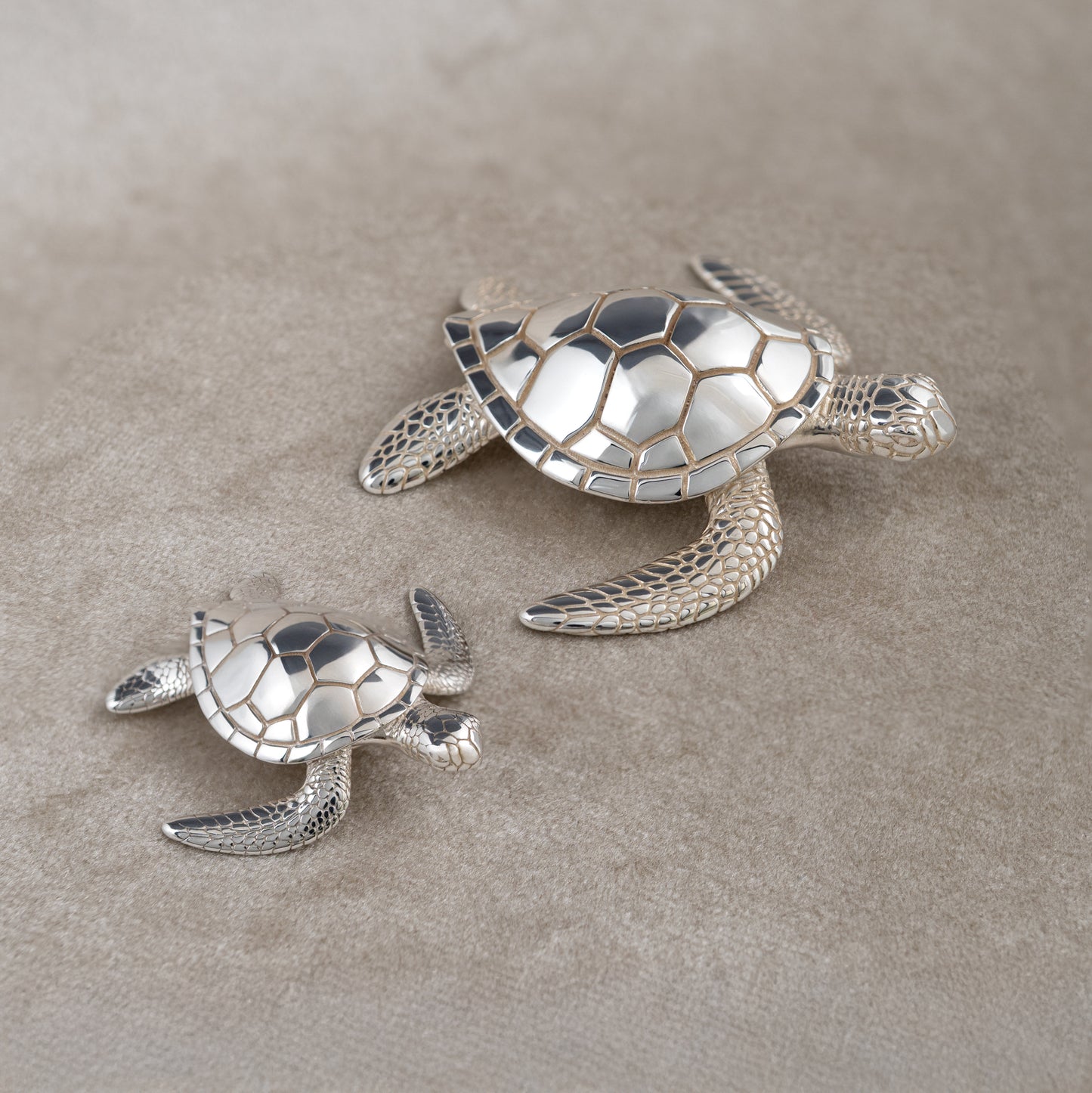 Sterling silver sea turtle figurines small and large on soft beige background