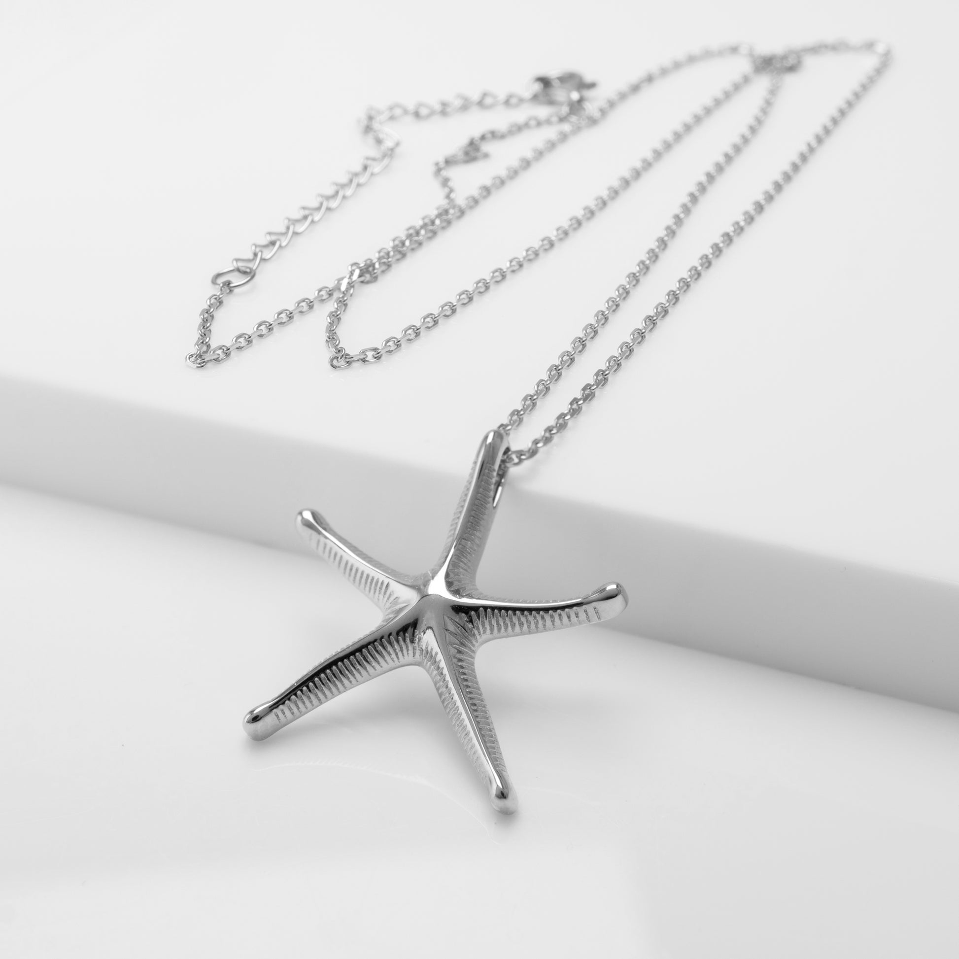Silver starfish pendant necklace on a white background