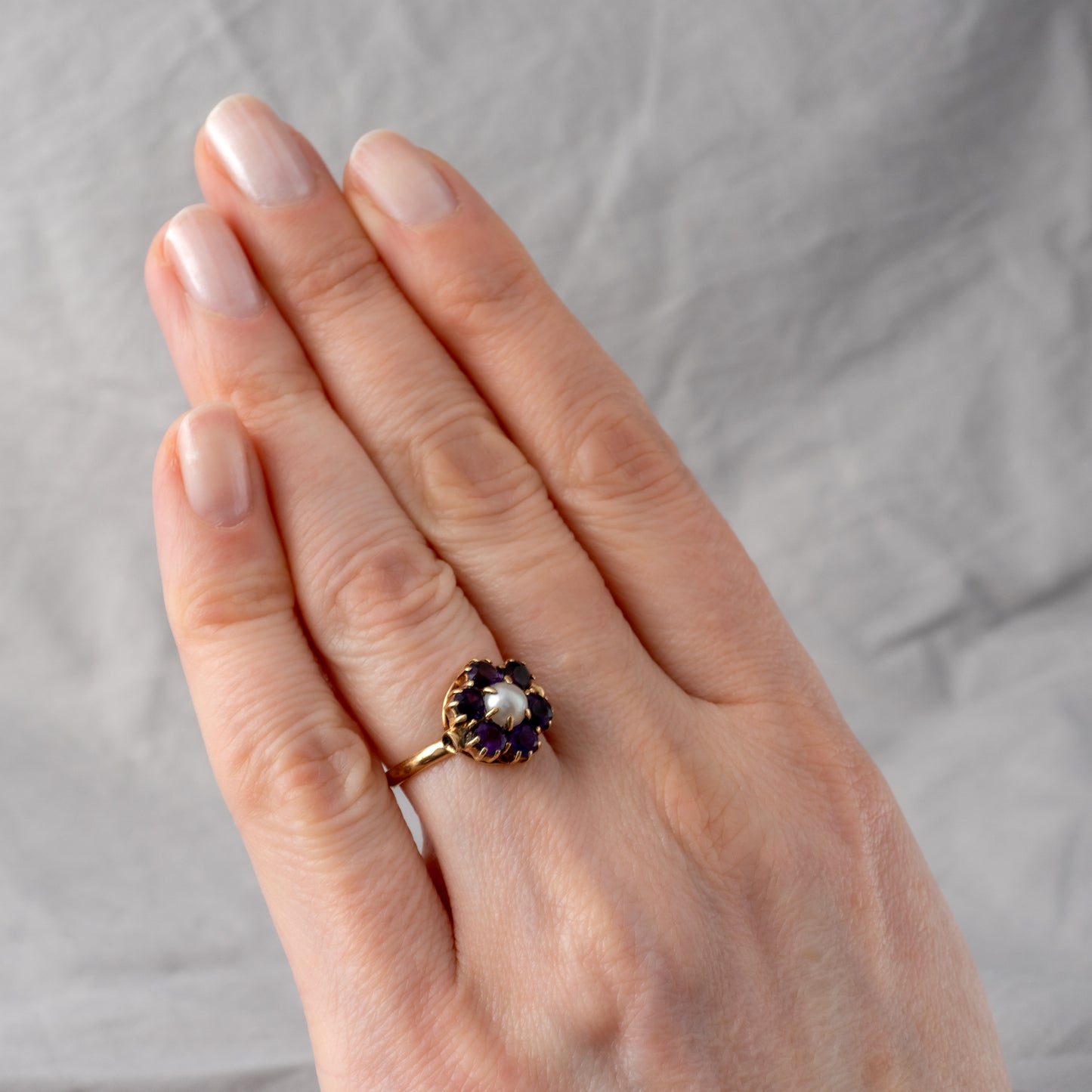 woman hand wearing vintage flower ring with amethyst pearl