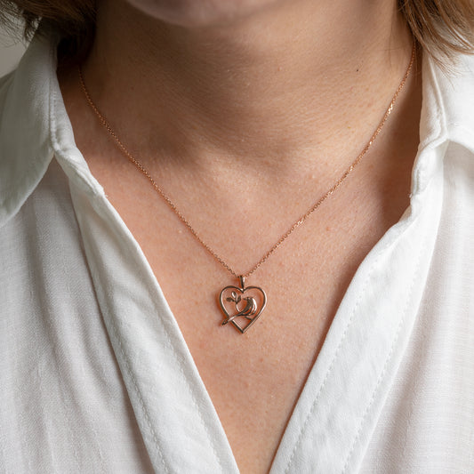 woman wearing 375 rose gold bird in heart necklace by hunters fine jewellery