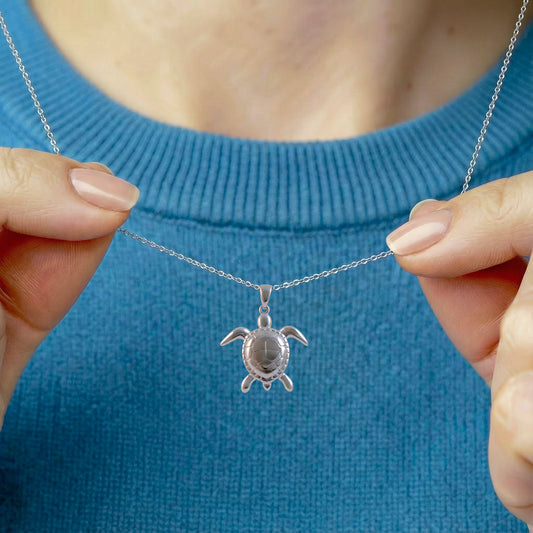 woman wearing silver sea turtle necklace with ocean blue jumper