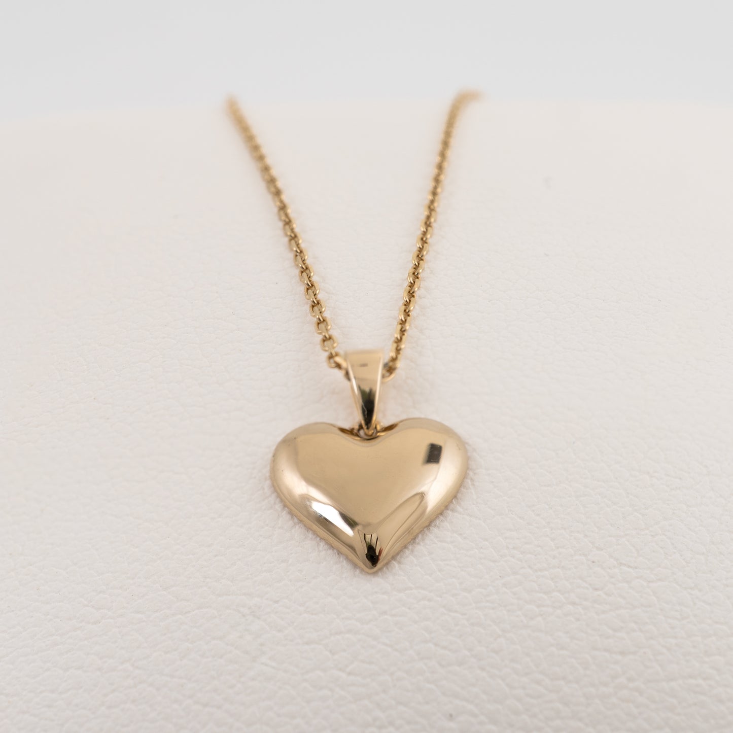 Yellow gold heart necklace with smooth polished finish on white display