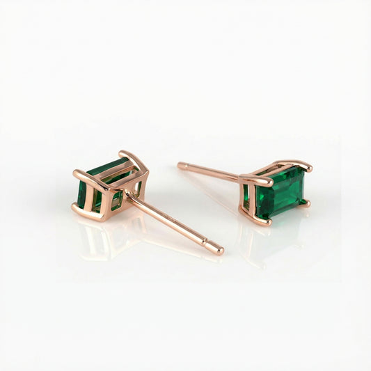Rose gold earrings with green gemstones on a white background