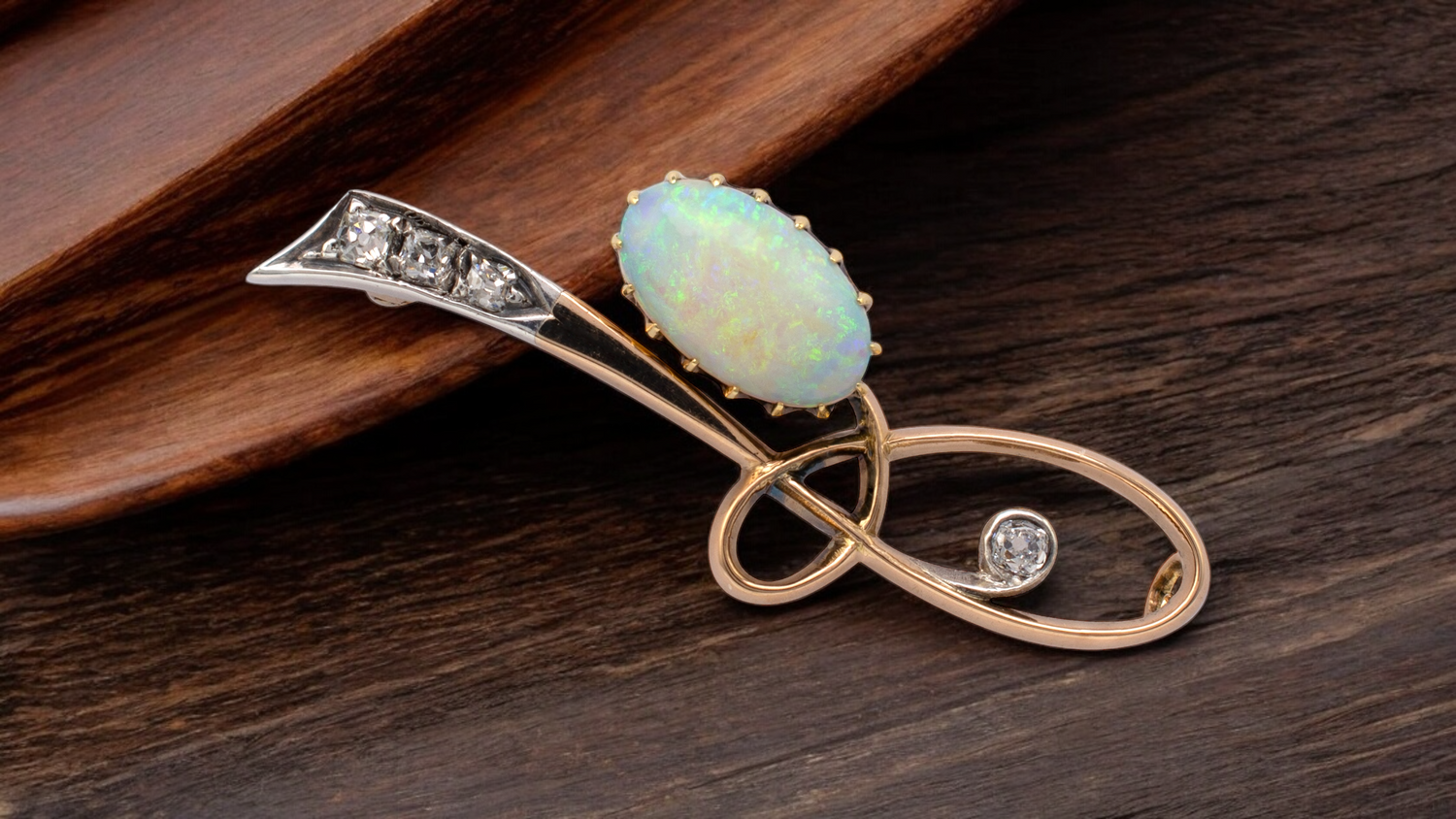 Antique opal and diamond brooch in gold setting on wooden surface