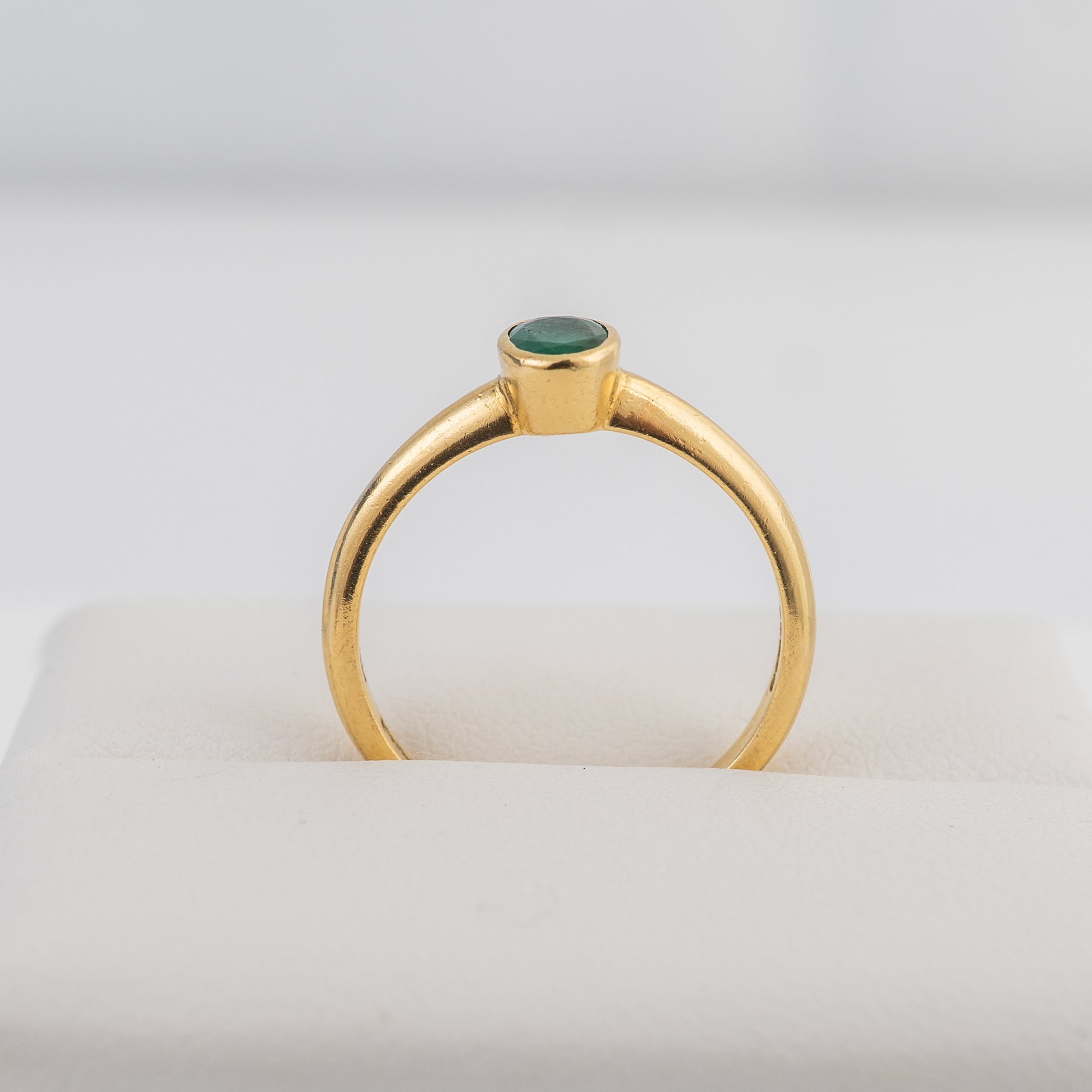 End profile of an 18ct gold emerald solitaire ring with a bezel-set oval emerald