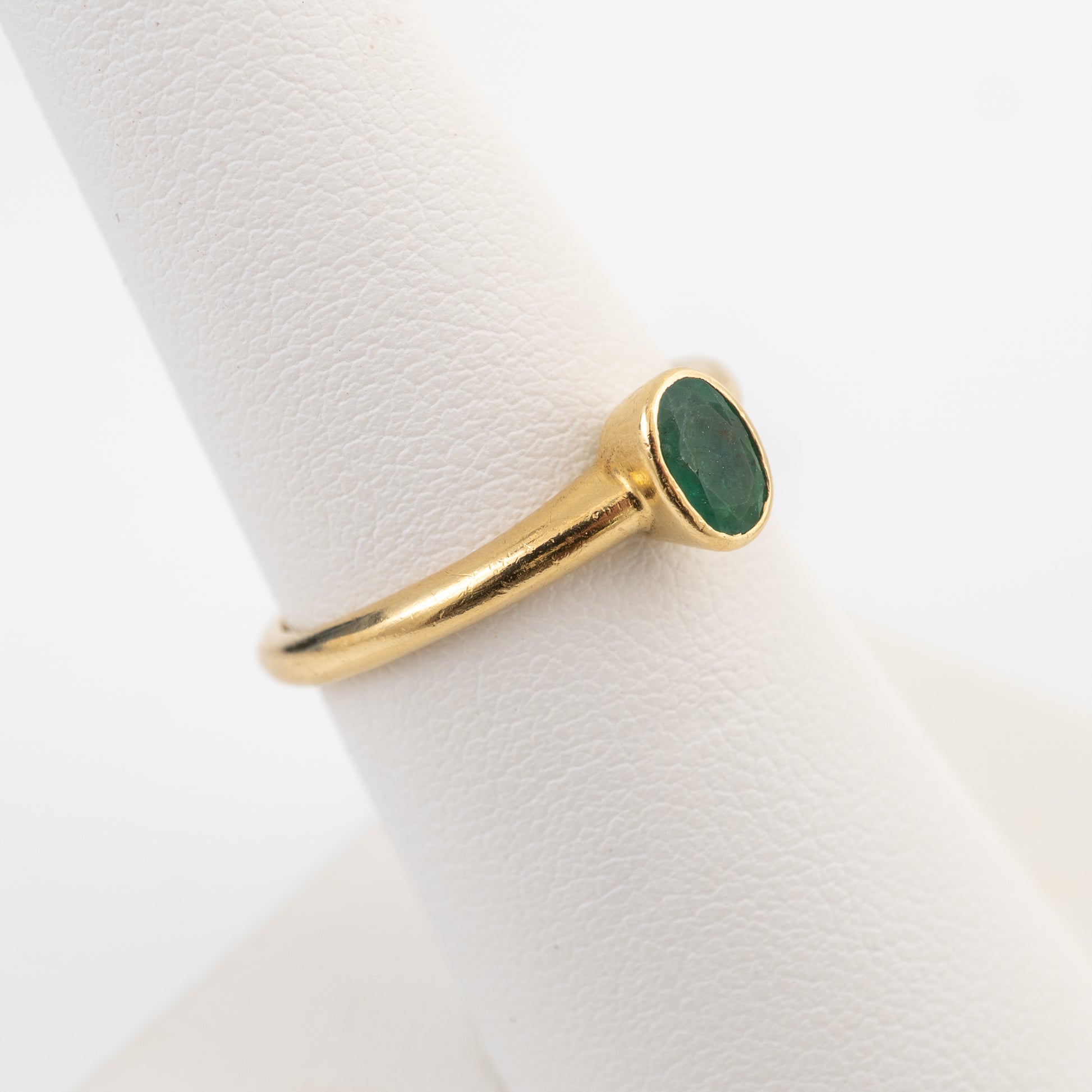 18ct gold emerald solitaire ring shown on a ring stand