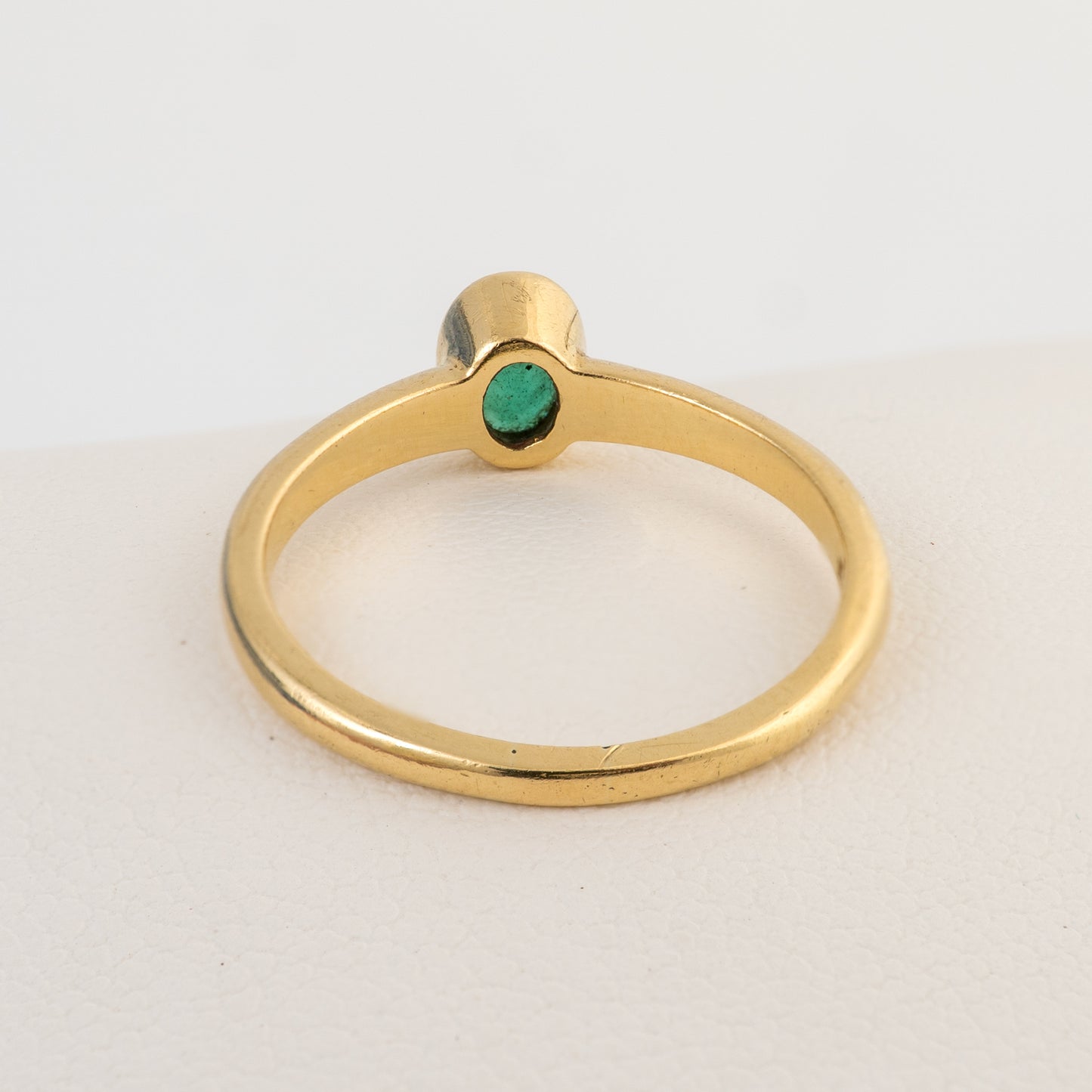 Rear view of an 18ct gold emerald solitaire ring showing the bezel setting
