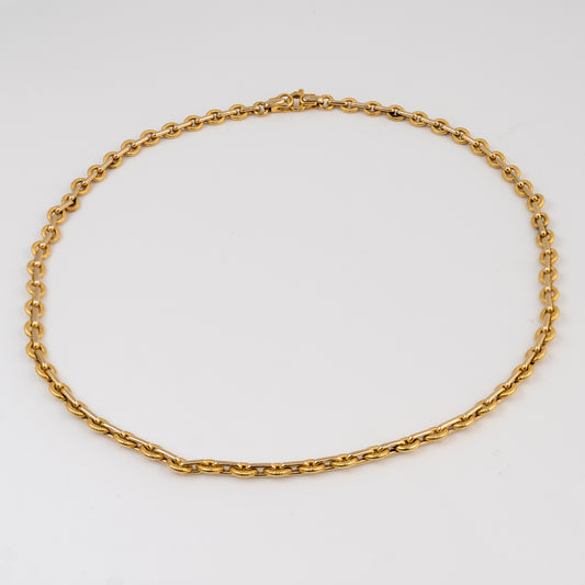 A yellow gold chain necklace with a classic curb link design, arranged in a neat circle on a clean white background.