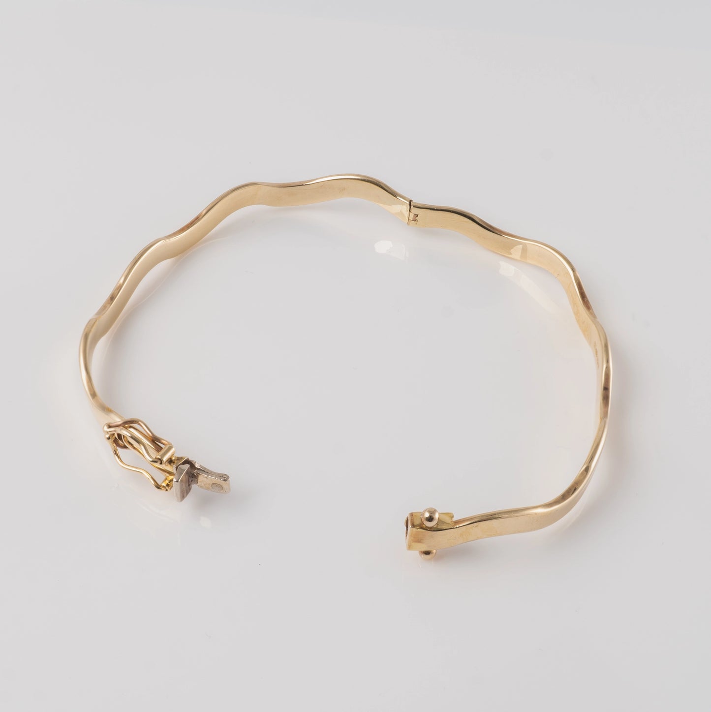 375 gold wave bangle bracelet – fully opened hinged design on white background.