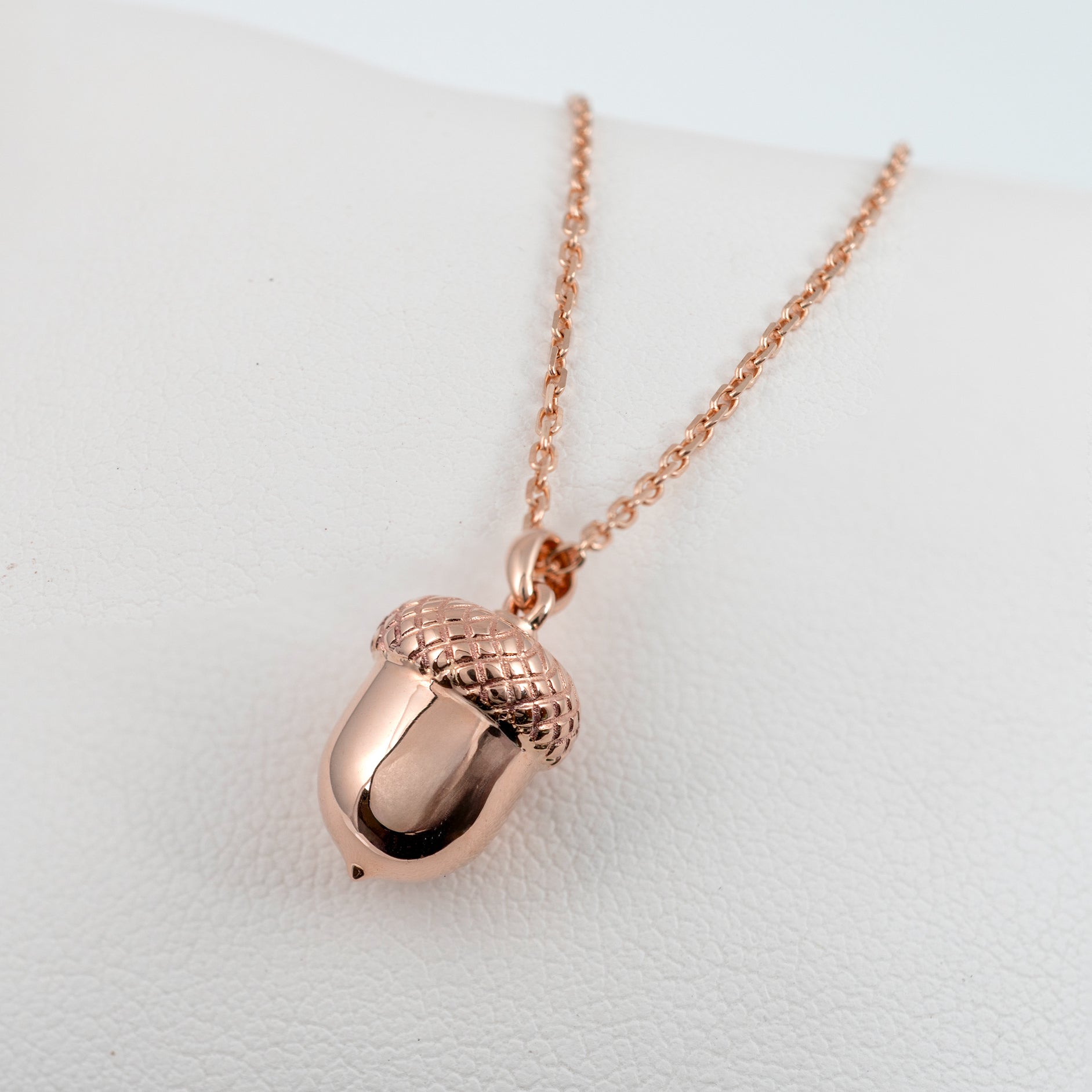Rose gold acorn pendant necklace on a light gray background