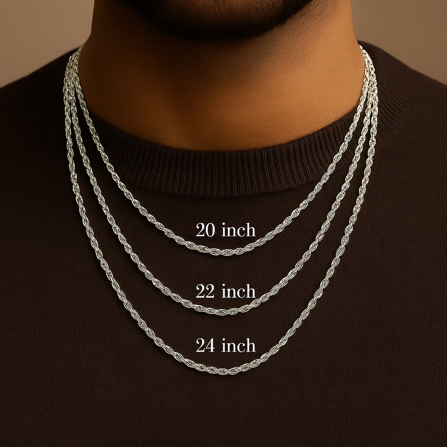 Three silver chains of different lengths displayed on a male models neck against a brown background.