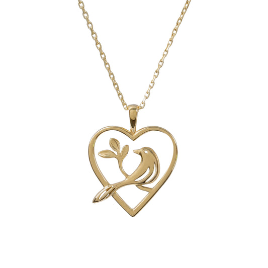 A gold necklace featuring a heart-shaped pendant with a bird perched on a branch, shown against a plain white background.
