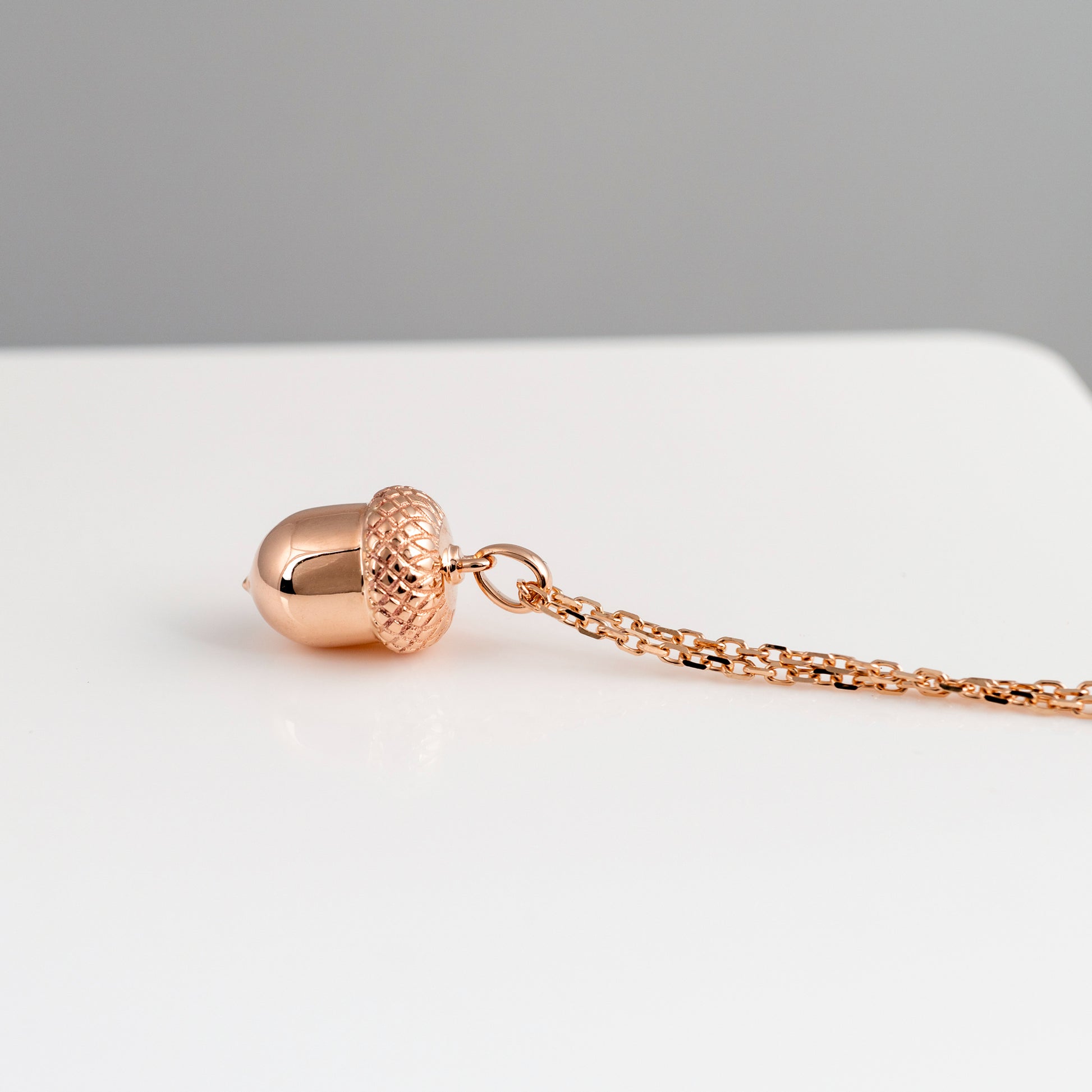 Rose gold necklace with a unique pendant on a light gray background