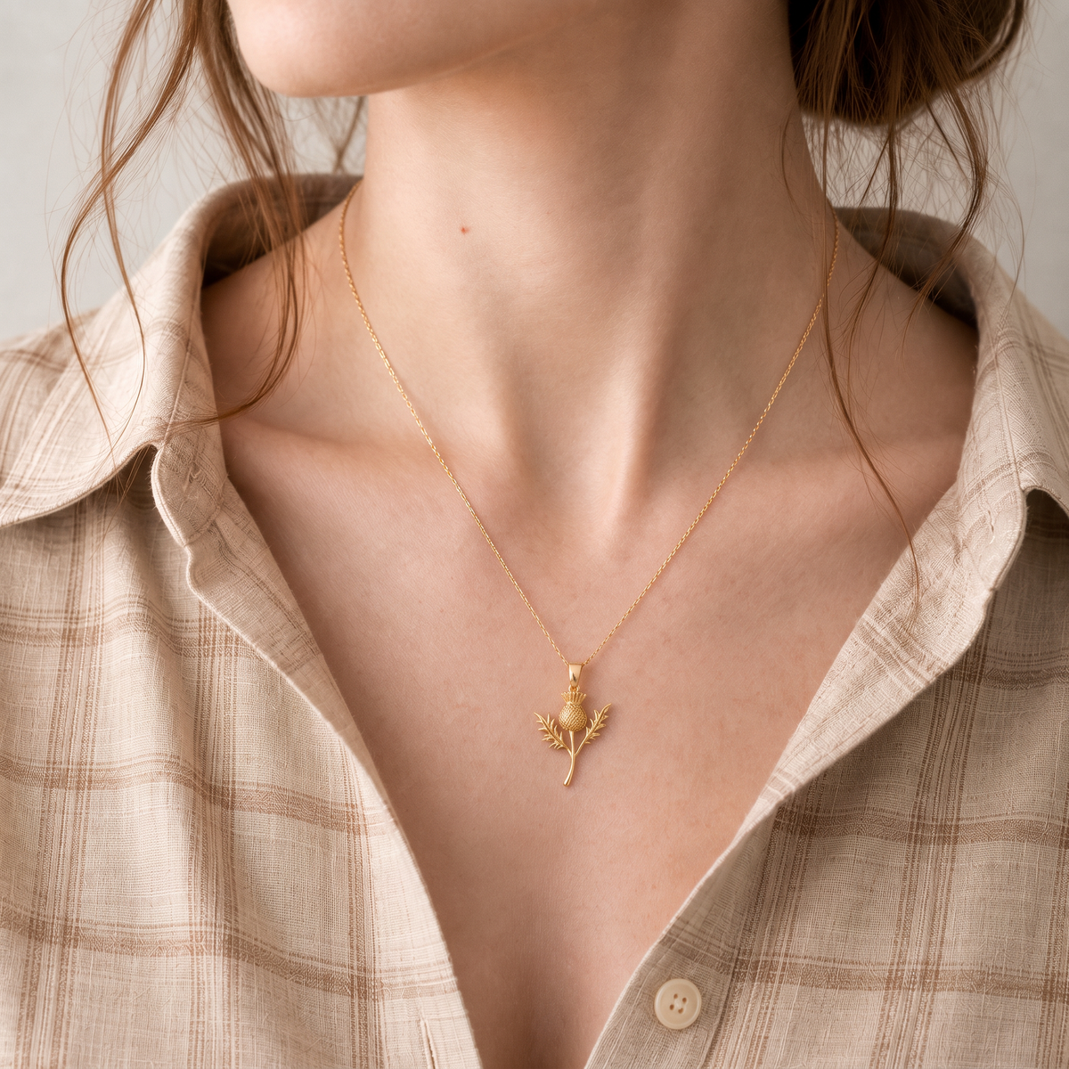 woman wearing gold scottish thistle necklace with neutral tartan shirt
