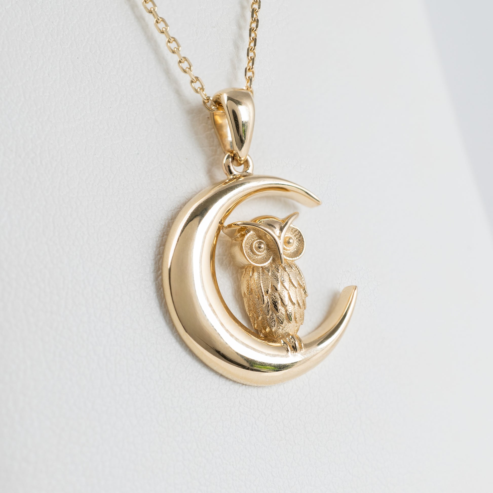 Close-up of owl and crescent moon pendant in solid yellow gold