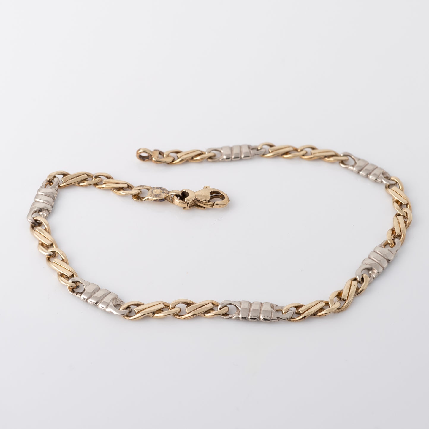 Full view of 9ct figaro bracelet gold chain showing white gold connectors and lobster clasp