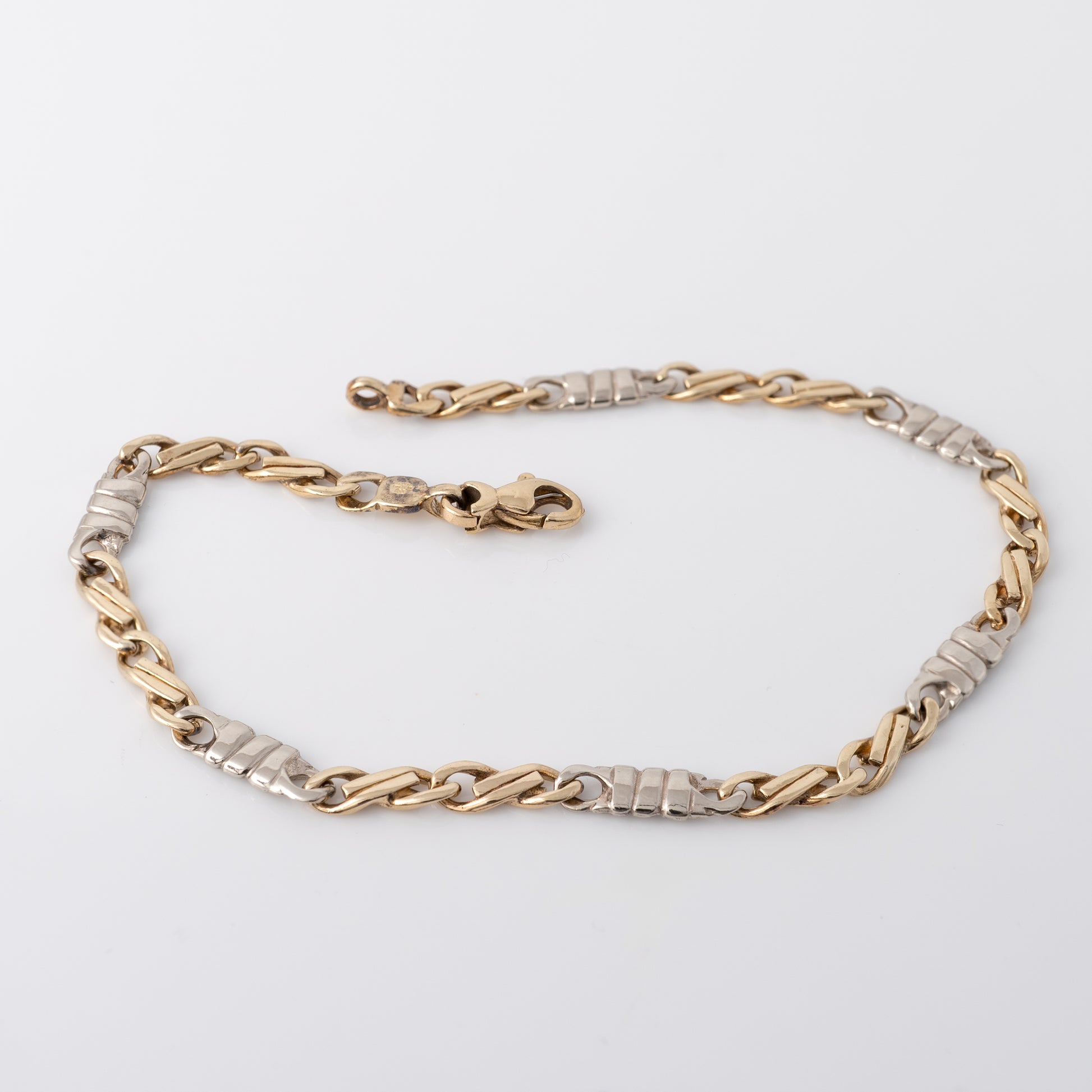 Full view of 9ct figaro bracelet gold chain showing white gold connectors and lobster clasp