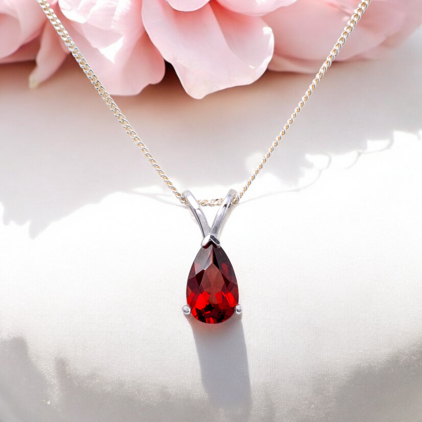 garnet teardrop necklace displayed with pink flower