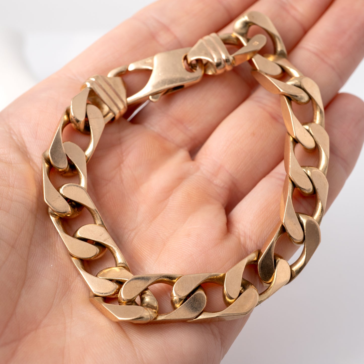 Gents heavy gold curb bracelet held in hand, showcasing sturdy lobster clasp