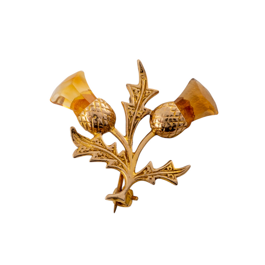 Gold Scottish thistle brooch with faceted citrine gemstones on a white background