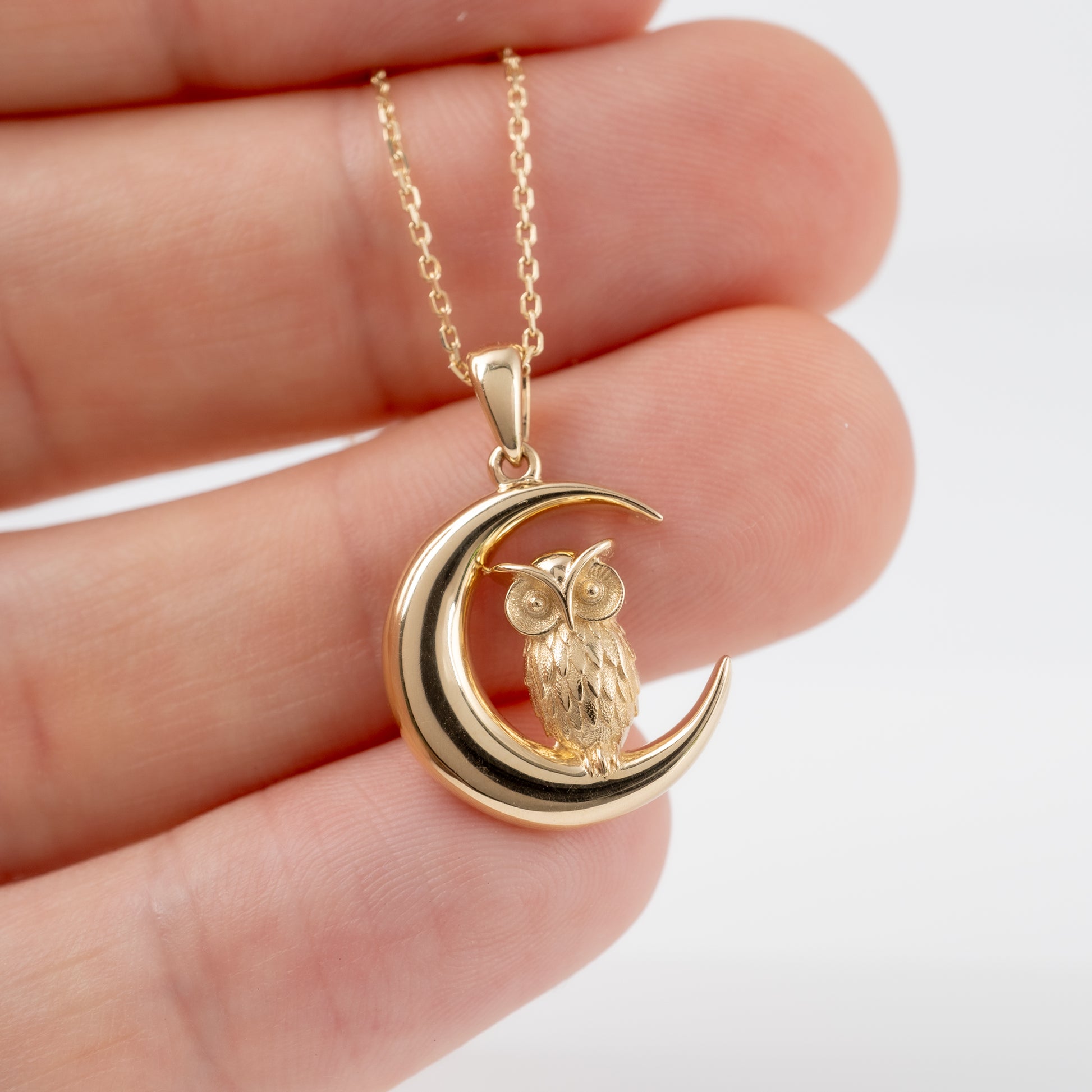 hand-holding-gold-owl-pendant