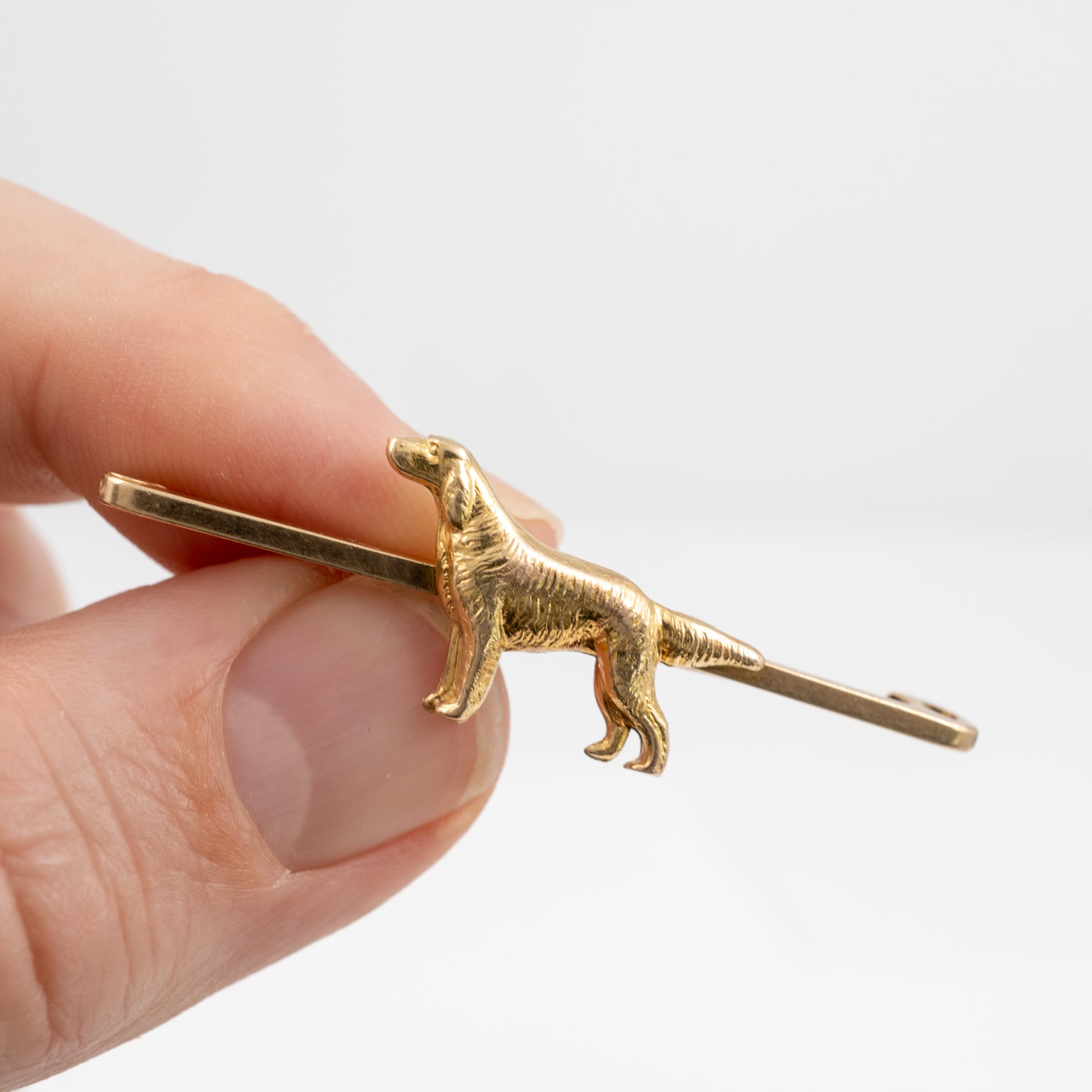 Hand holding a vintage 9ct gold dog brooch featuring a Golden Retriever, showcasing its size and detail
