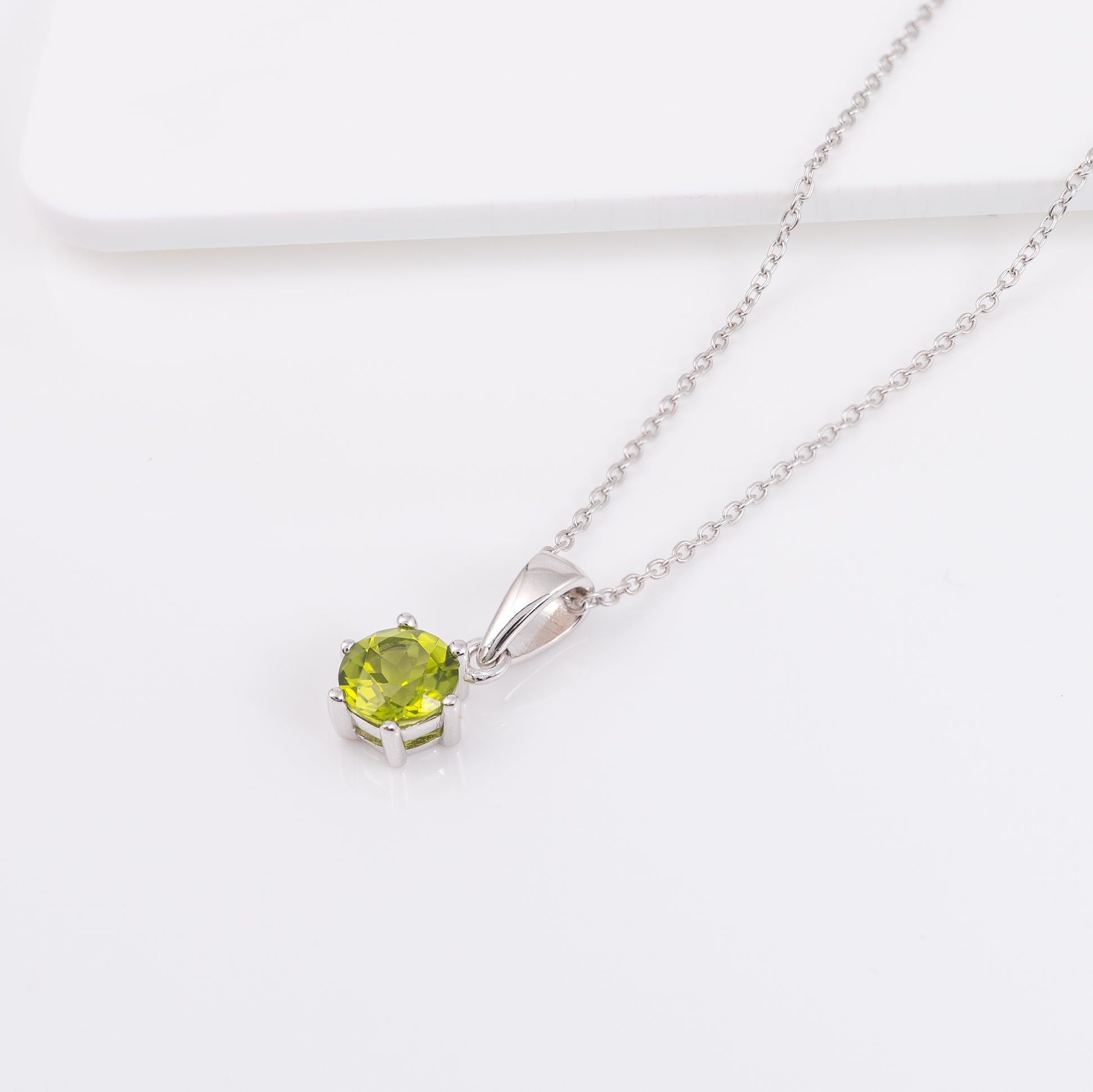 Silver necklace with a peridot pendant on a white background