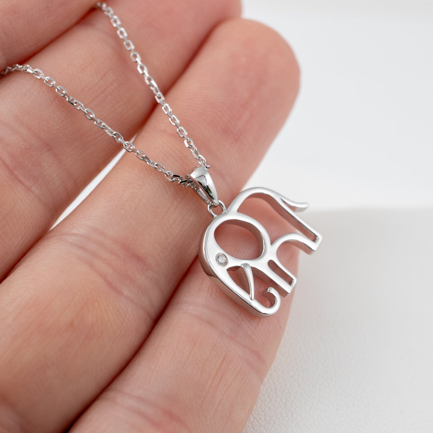 Small sterling silver elephant necklace pendant shown in hand